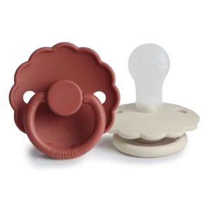 A 2-pack of FRIGG Daisy silicone pacifiers in baked clay and cream, designed for soothing babies aged 0-6 months with a secure click-lock system.