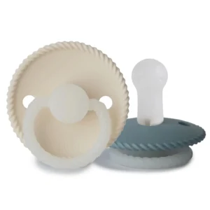 Two-pack of FRIGG Rope pacifiers in cream and stone blue with glow-in-the-dark handles and round, latex-free silicone nipples, designed to mimic breastfeeding.
