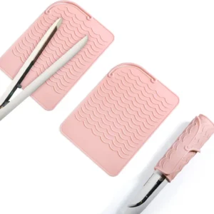Pink silicone heat resistant mat safely holds hot curling iron and hair straightener, protecting surfaces from heat damage with its non-slip wave design and convenient hanging strap.
