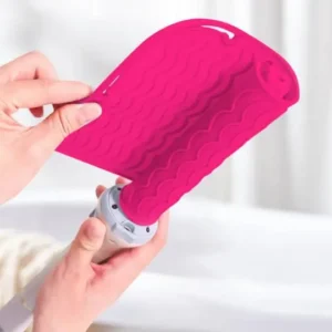 Red silicone heat resistant mat for protecting surfaces from hot hair styling tools like curling irons and flat irons.
