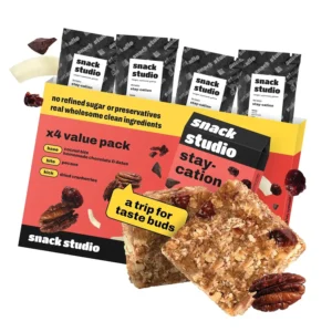 Four snack studio stay-cation snack bars made with coconut, cranberries, pecans, and dark chocolate for a healthy and natural snack.